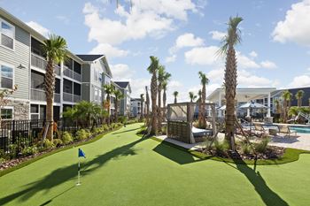 A miniature golf course is surrounded by palm trees and a pool.